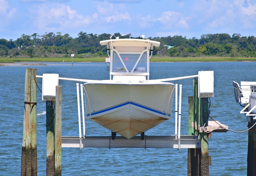 Boat raised on a lift over a Hampton Roads tidal river beside a timber dock